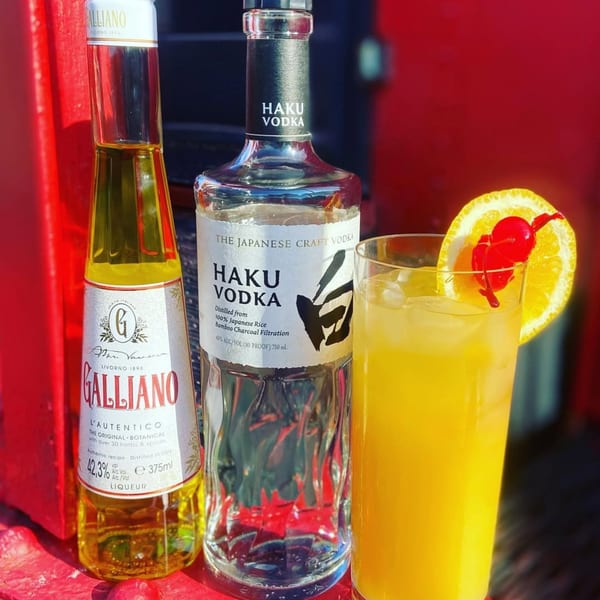 Galliano liqueur, Haku vodka, and a cocktail with orange slice and cherry garnish.