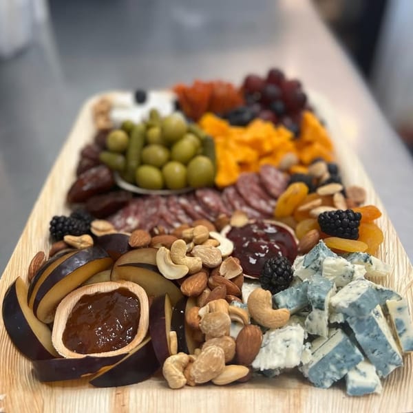 A charcuterie board with various cheeses, meats, nuts, fruits, and jams.