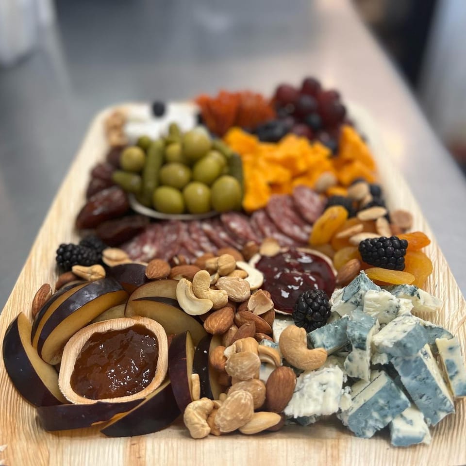 A charcuterie board with meats, cheeses, olives, nuts, dried fruit, and jam.